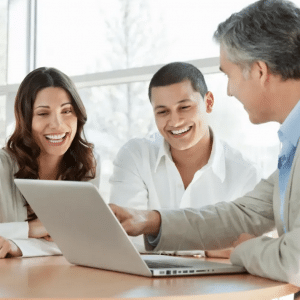 Trois personnes souriantes regardent un ordinateur portable.
